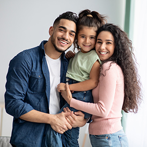 Portrait Of Happy Arabic Parents Posing With Their Little Daughter At Home