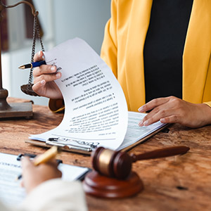 Professional reviewing legal contracts; document drafting services with a gavel and justice scales.